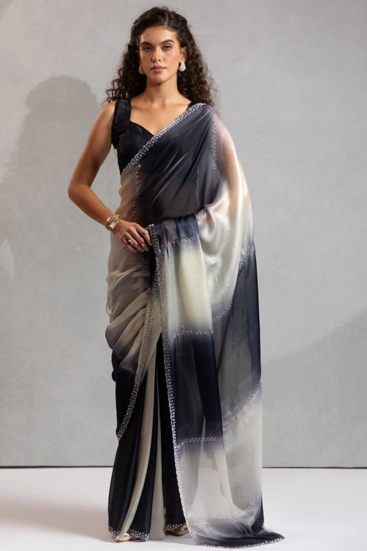 Woman wearing a black and white saree with a plain background