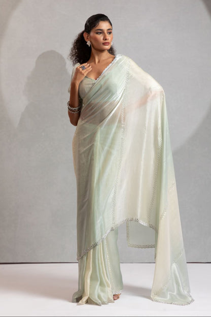 Woman wearing a light-colored saree against a neutral background